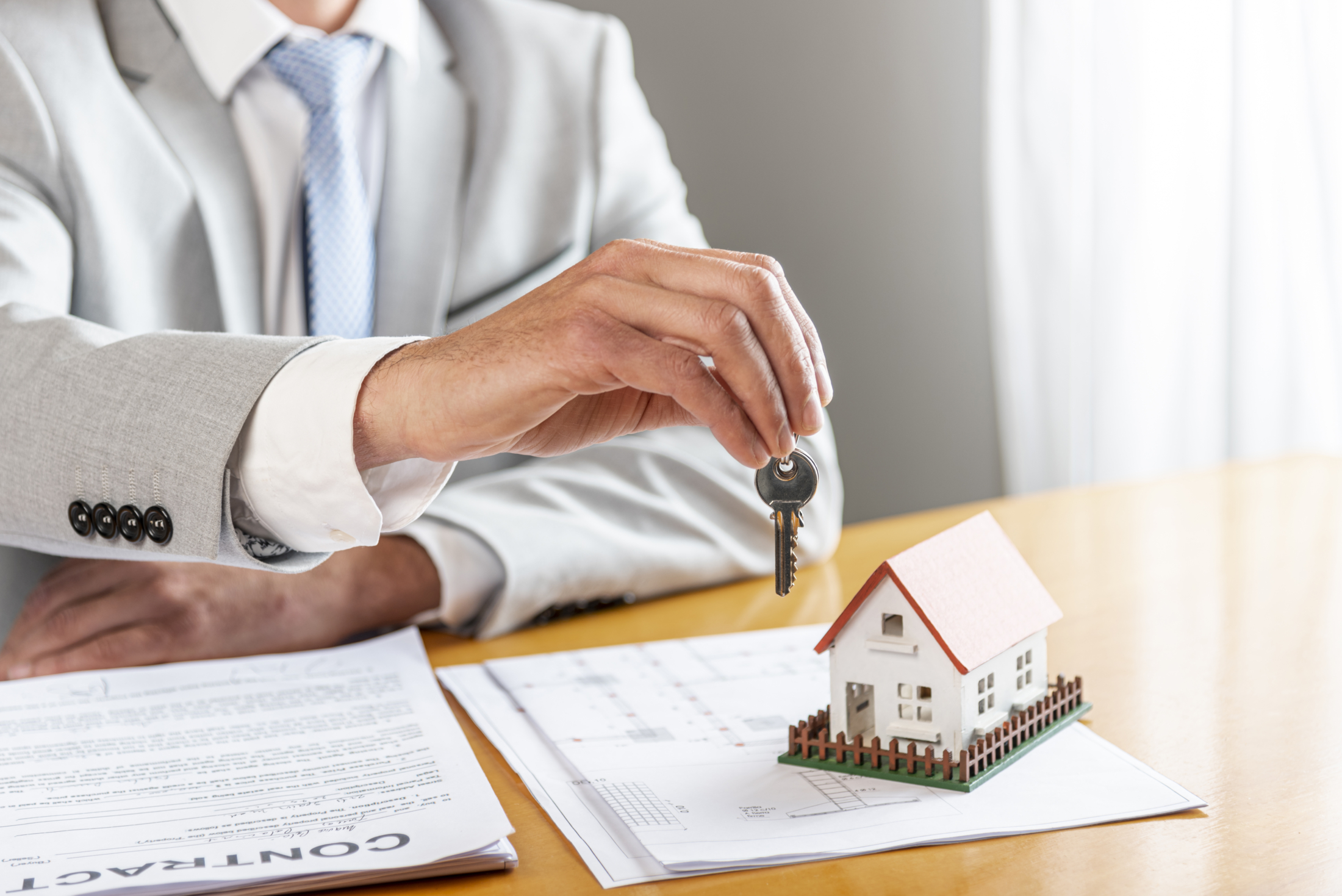 Person Holding House Keys Toy Model House Desk